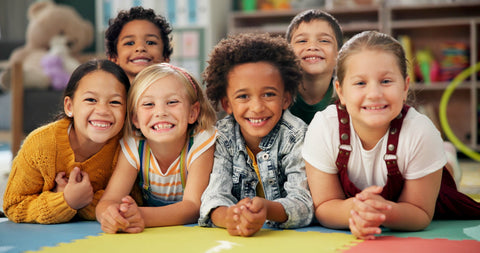 Group of children lying on a colorful mat in a classroom setting