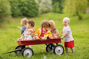 Children playing with a red wagon in a grassy field after using Luna and Eve toddler multivitamin powder