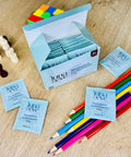 Luna & Eve multivitamin packets on a wooden surface with colorful pencils.